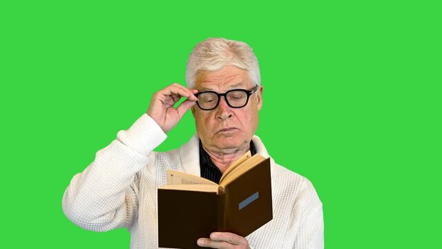 Senior man reading a book on a Green Screen, Chroma Key.