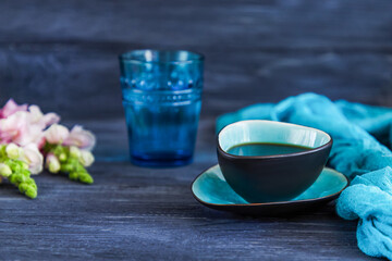 Coffee in a turquoise cup, a glass of water and snapdragons flowers