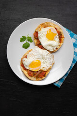 Fried eggs with sauce and tortilla called rancheros for  breakfast on dark background. Mexican food