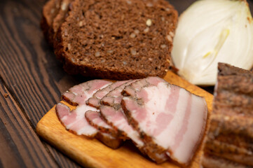 Smoked brisket sliced and grain bread on a wooden chopping board.
