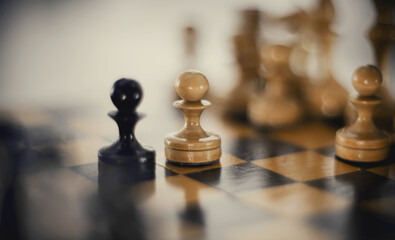 Two chess pieces are pawns: black and white. Wooden chess pieces on the chessboard.