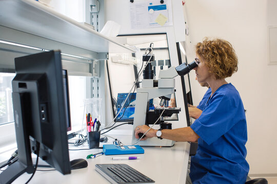 Profile of Female Lab Technician Working on Microscope in Bright
