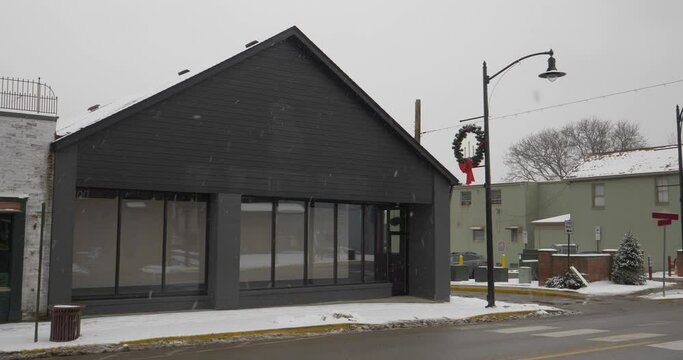 A daytime winter establishing shot of an unbranded storefront in the business district of a small town. Blank marquee for customization.	