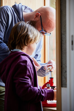 Father And Son Examining Shell By Window At Home