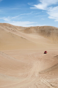 Red 4x4 vehicle in the middle of sand dunes of the desert
