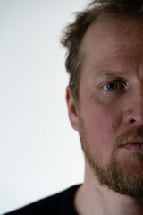 half of a serious portrait of a man close-up on a white background with a very serious face and gaze