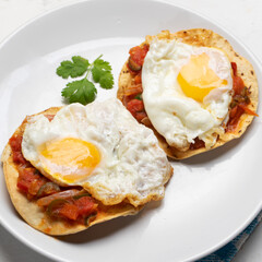 Fried eggs with sauce and tortilla called rancheros for  breakfast on white background. Mexican food