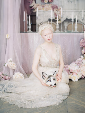 Young albino woman with domesticated white and black fox