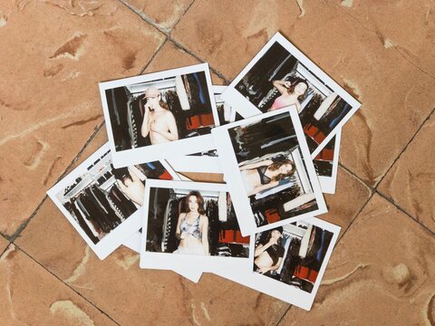 Sexy girl in cap covering breast on polaroid shot