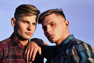 Caucasian twins in shirts with serious faces. Future and freedom, support and trust. Fashion for men, summer. Mans friendship