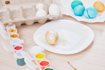process of painting eggs for easter, eggs box, easter eggs, plate, brushes and paints on the table