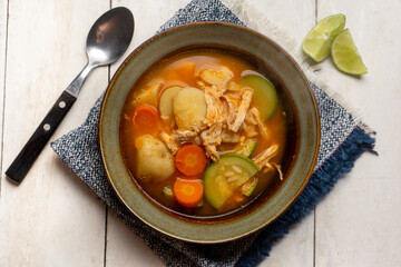 Chicken soup with rice and vegetables on white background