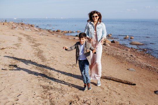 Mother and son running and playing at the beach near the sea