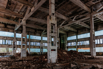 Fototapeta na wymiar Abandoned ruined large industrial hall with garbage waiting for demolition