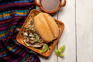 Confit pork sandwich called Torta de carnitas on white background. Mexican food
