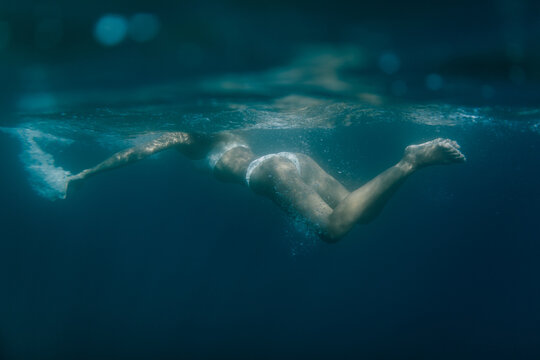 Wide shot of a woman swimming underwater