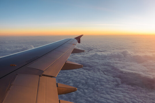 Airplane wing shot above the clouds at sunrise