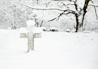 Headstone in the shape of a cross is covered in snow