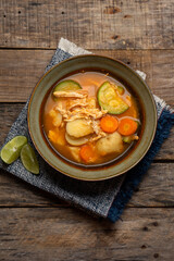 Chicken soup with rice and vegetables on wooden background
