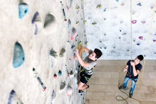 Two teenager friends rock climbing on an indoor wall