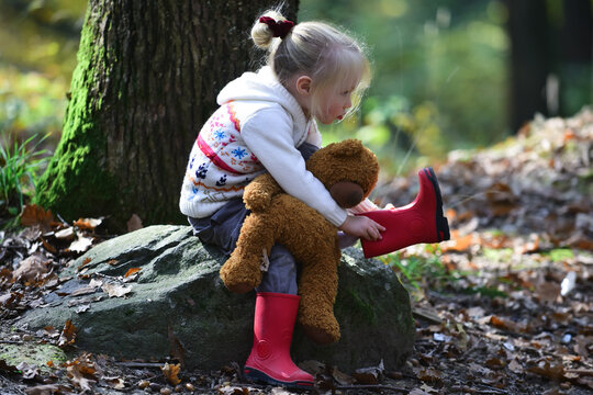 Little child tumn forest with teddy bear. Baby exploring nature on fall day.