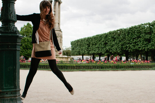 Young woman swings on light post in Paris