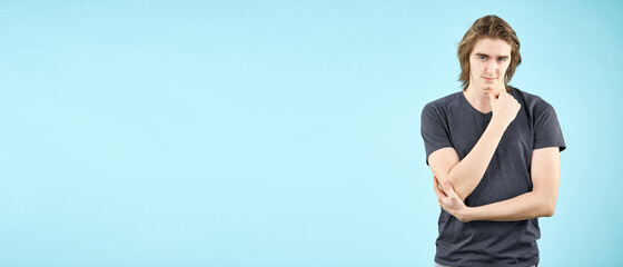Portrait of an emotional young man in a T shirt posing for the camera isolated on a blue background