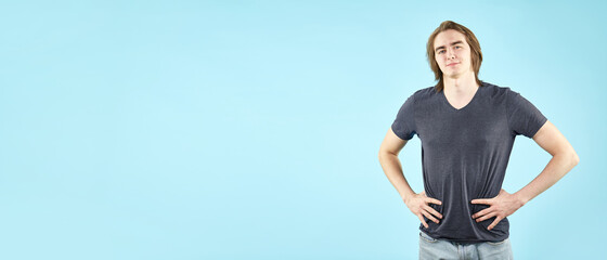 Portrait of an emotional young man in a T shirt posing for the camera isolated on a blue background