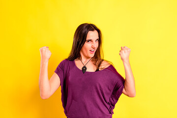 Young woman with proud attitude for a triumph and her achievements made by herself, isolated on yellow background.