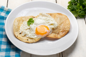 Fried egg and corn tortilla for breakfast on white background