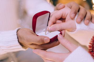 She said yes. A man proposes to his girlfriend on Valentine's Day. The woman takes the ring from the box. Close-up of hands.