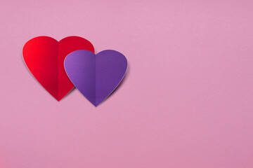 Decorative background for Valentine's Day cards. On a pink background, two decorative paper-cut hearts of red and purple colors.