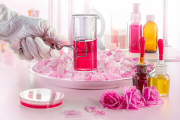 A hand in a glove holding a clip with a test tube in up-to-date perfume laboratory. Background...
