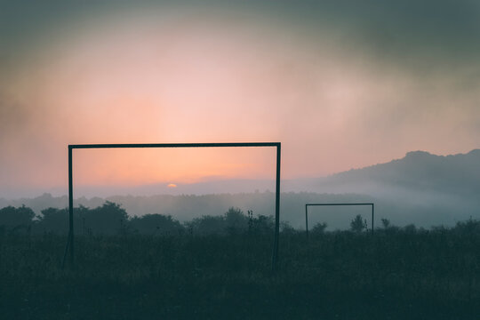 Abandoned football field at sunrise with fog