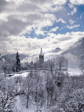 Bell tower of a church nestled in a mountain landscape surrounded by snow