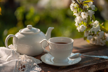 Tea set, cherry blossom branches, wooden table. Outdoor breakfast, picnic, brunch, spring mood. Soft focus