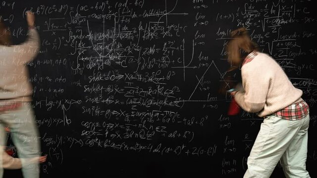 A mathematics professor is writing algebra formulas on a blackboard in looped time lapse. Concept of science and academic achievements. Teacher is focused on studies and explains math material. - Powered by Adobe