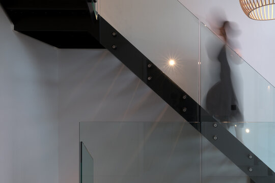 Modern metal staircase with blurred woman ascending.