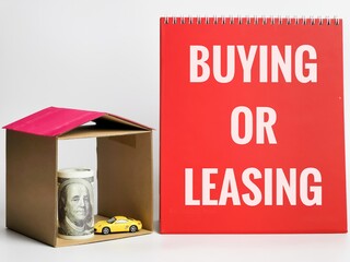 Phrase BUYING OR LEASING written on red board with miniature house,car and fake money. Property concept.