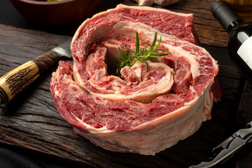 strip of roast beef, fresh beef ribs, on wooden board with vegetables and rotisserie knife with pepper mortar and knife and fork.