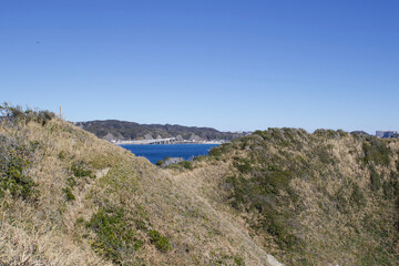 Katsuura Bay in Chiba Japan view, the ocean is a stunning deep blue color and the day is clear. It is a very idyllic scene. High cliffs and green hills.