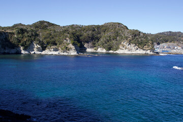 Fototapeta premium Katsuura Bay in Chiba Japan view, the ocean is a stunning deep blue color and the day is clear. It is a very idyllic scene. High cliffs and green hills.