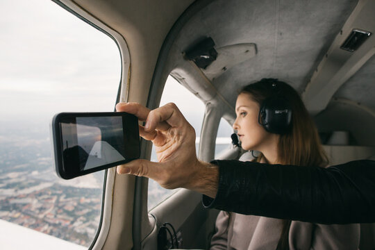 Closeup of Hand of Male Passenger in Private Jet Taking Smartpho