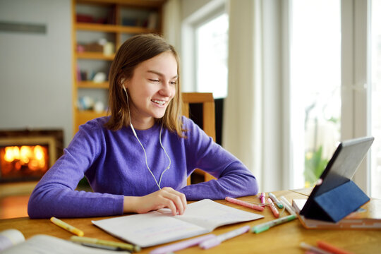 Preteen schoolgirl doing her homework with digital tablet at home. Child using gadgets to study. Education and distance learning for kids. Homeschooling during quarantine.