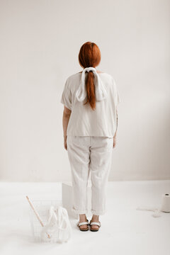 creative portrait of woman with red hair wearing all white with white string tied in her hair