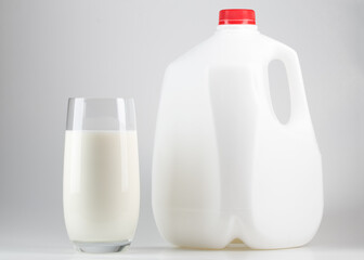 Milk. Glass of milk and one gallon of whole milk. Organic milk product. White plastic bottle one...