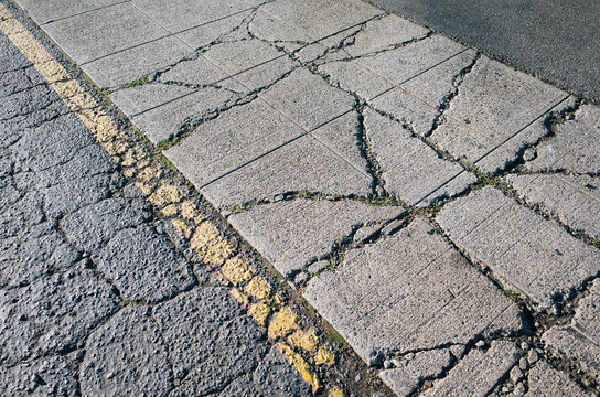Detail of worn urban sidewalk and yellow boundary line