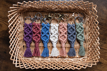 Seven (7) cotton macrame keychains are displayed in a wicker basket.