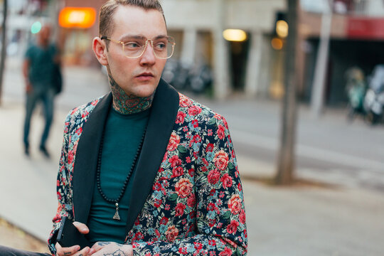 Tattooed handsome man with colourful flower jacket around the city.