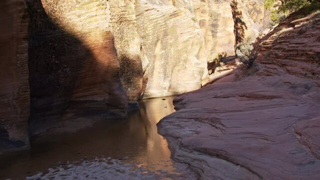 Water in slot canyon iced over in the Utah desert hiking on the sandstone.